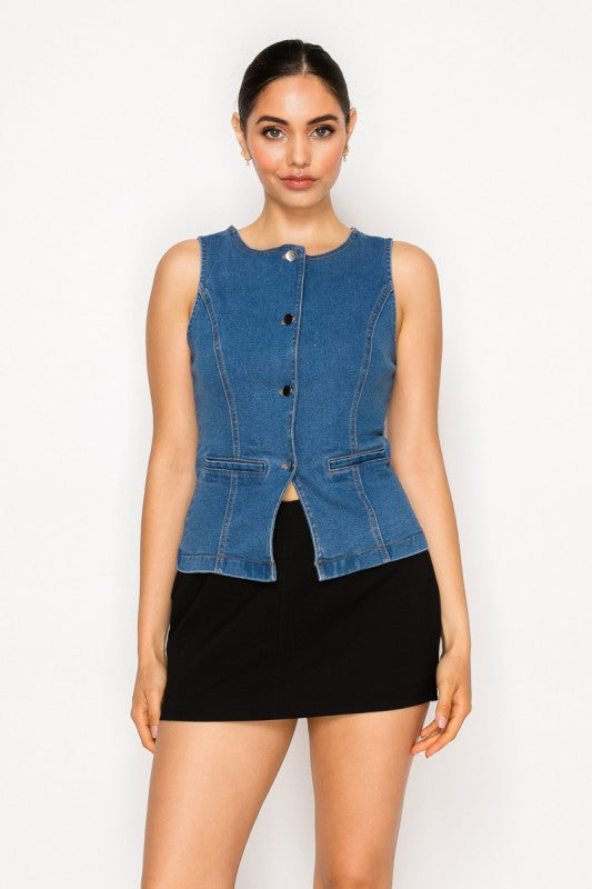 A model wearing a sleeveless blue denim vest with front buttons and a black mini skirt, standing against a plain white studio background.