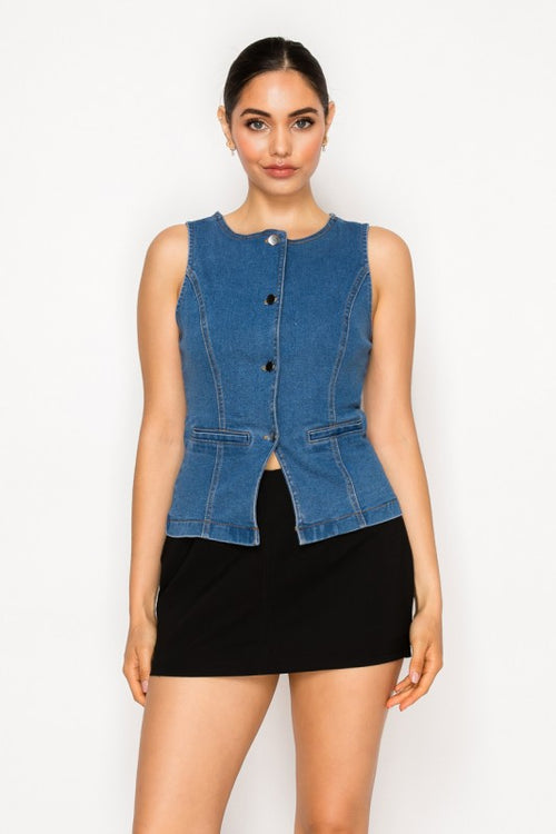 A model wearing a sleeveless blue denim vest with front buttons and a black mini skirt, standing against a plain white studio background.