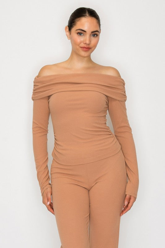 Woman wearing a tan off-shoulder jumpsuit on a white background