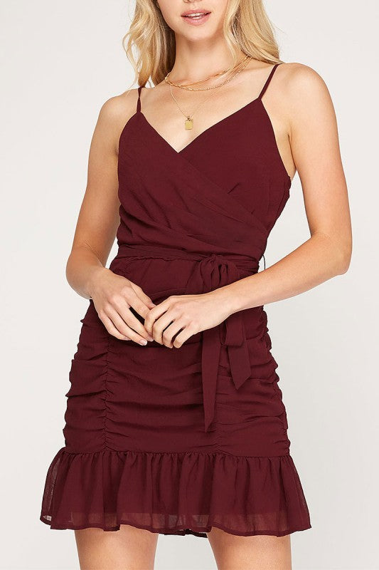 Woman wearing a burgundy dress with thin straps on a white background
