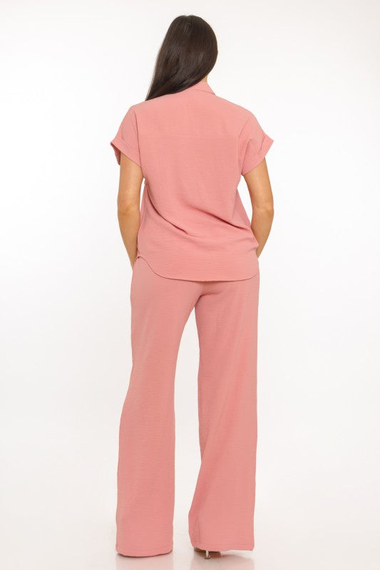 Woman wearing a pink outfit with a top and wide-leg pants on a white background