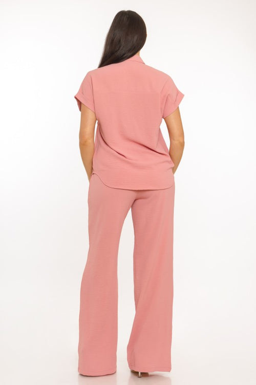 Woman wearing a pink outfit with a top and wide-leg pants on a white background