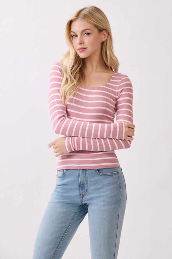 Woman wearing a pink and white striped long-sleeve top and light blue jeans on a white background