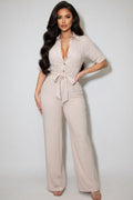 Woman wearing a beige jumpsuit against a white background