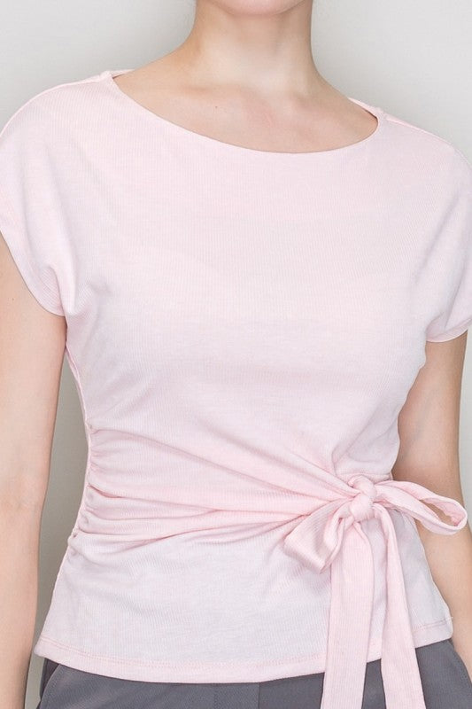 Light pink top with a tie detail on a plain background