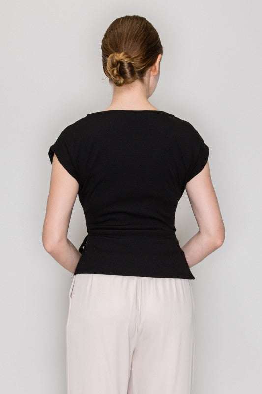 Person wearing a black top and light-colored pants against a plain background