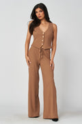 Woman wearing a brown sleeveless top and wide-leg pants on a white background