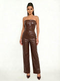 A woman modeling a brown faux-leather strapless jumpsuit with a structured corset-style bodice and wide-leg pants, standing against a plain white studio background.