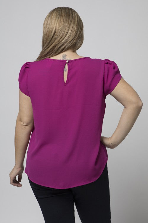 Magenta tulip blouse with black pants facing the back.