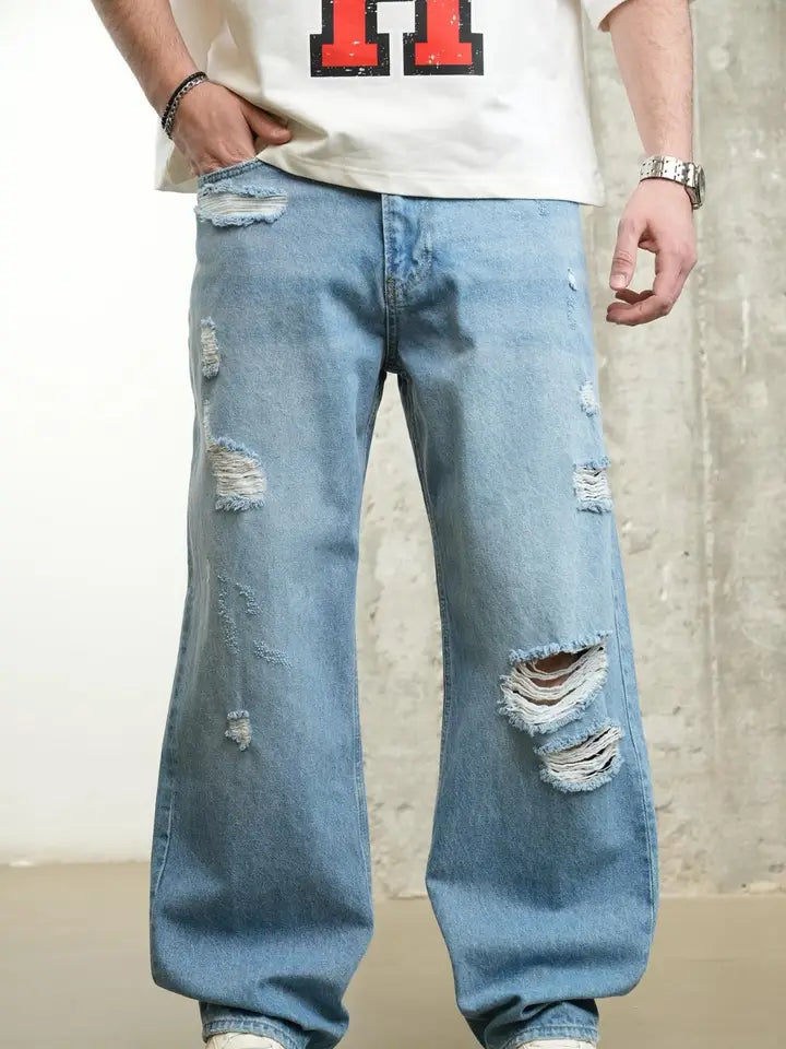 Person wearing ripped blue jeans with a plain background