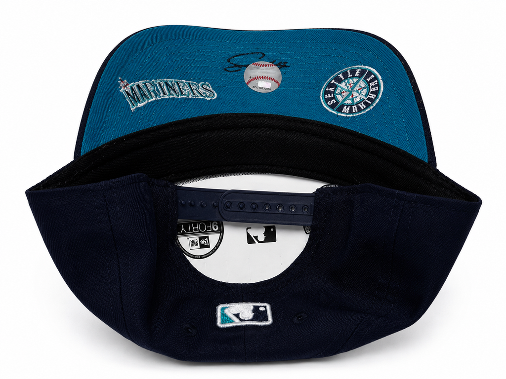 Navy Mariners snapback with bottom of hat showning Mariners team name and logo on underside of hat. 
