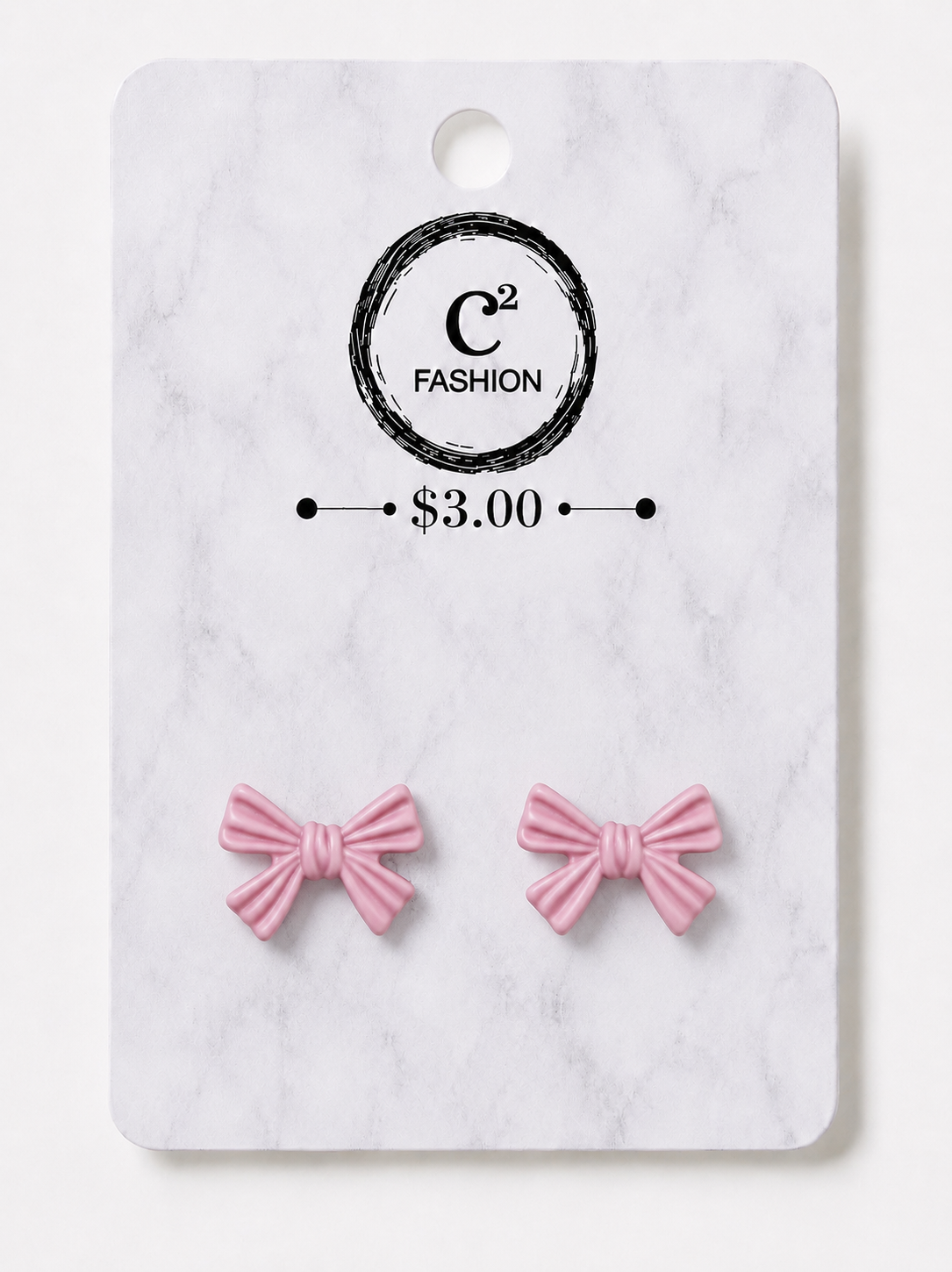 A pair of small pink bow stud earrings displayed on a white marble-style retail card with a circular logo reading C2 FASHION and a price of $3.00.