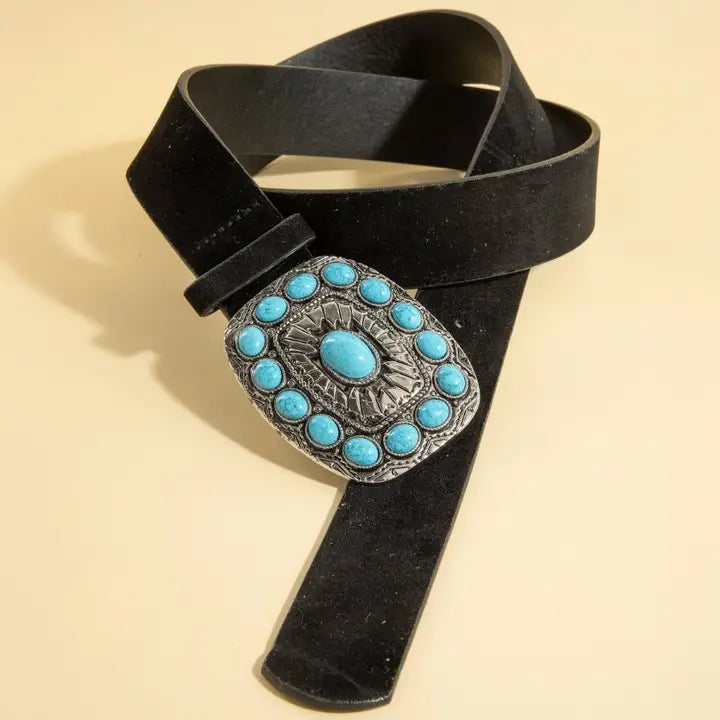 Black belt with a decorative buckle featuring turquoise stones on a beige background