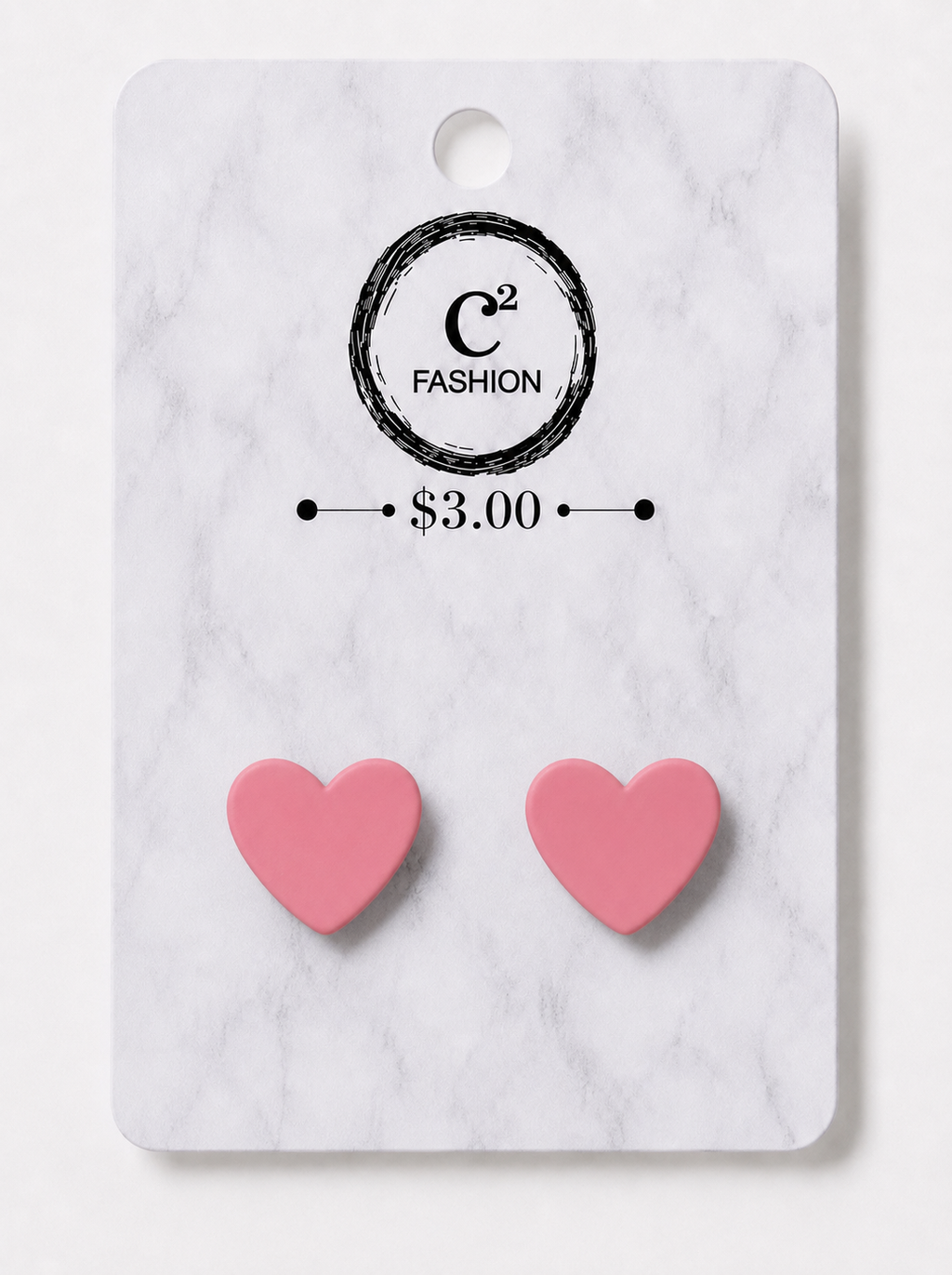 A pair of pink heart-shaped stud earrings displayed on a white marble-patterned retail card with the brand name C² FASHION and a $3.00 price printed on it.