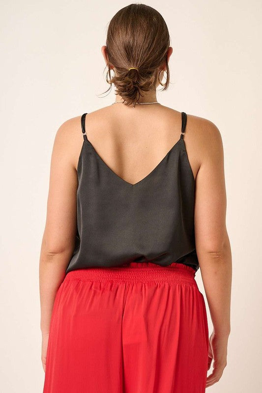 Person wearing a black top and red pants on a beige background