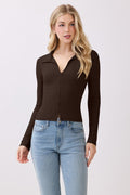 Woman wearing a brown long-sleeve top and blue jeans on a white background