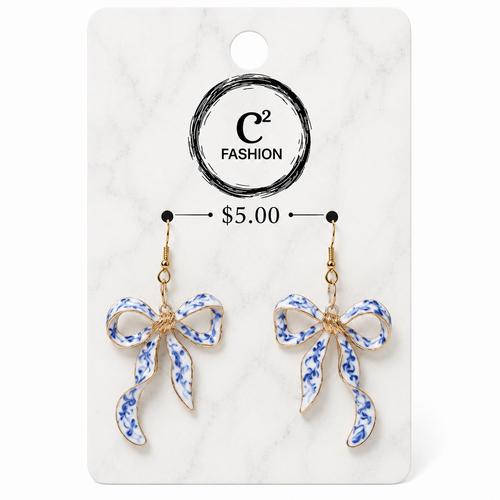 A pair of dangling bow earrings with blue and white floral enamel detailing and gold-tone hooks, displayed on a white marble-style retail card with the brand name C² FASHION and a price of $5.00.