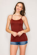 A woman modeling a rust-brown ribbed spaghetti-strap camisole tank top with blue denim shorts against a light gray studio background.