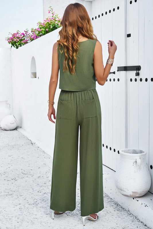 Woman wearing a green jumpsuit standing in front of a white door with decorative elements.