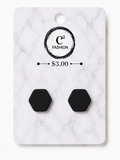 A pair of matte black hexagonal stud earrings displayed on a white marble-patterned retail card with the brand name C2 FASHION and a $3.00 price printed on it.