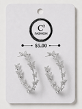 A pair of silver crescent-shaped hoop earrings decorated with small star and leaf motifs, displayed on a white C² FASHION brand card labeled $5.00.