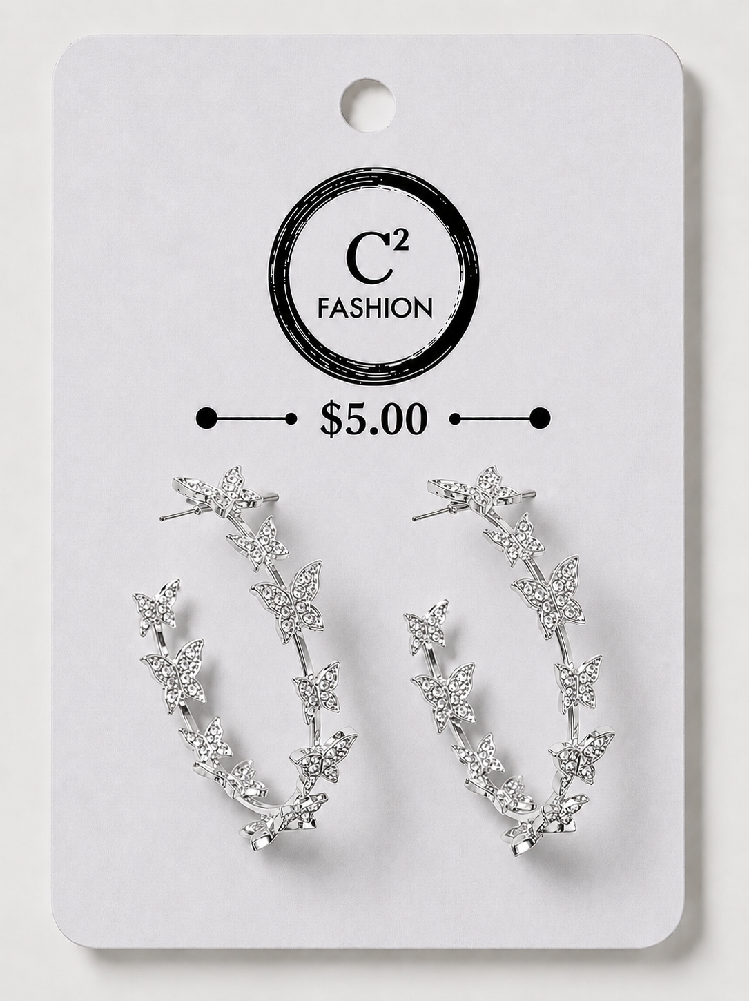 A pair of silver crescent-shaped hoop earrings decorated with small star and leaf motifs, displayed on a white C² FASHION brand card labeled $5.00.
