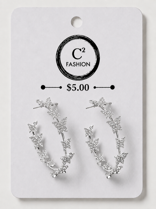 A pair of silver crescent-shaped hoop earrings decorated with small star and leaf motifs, displayed on a white C² FASHION brand card labeled $5.00.