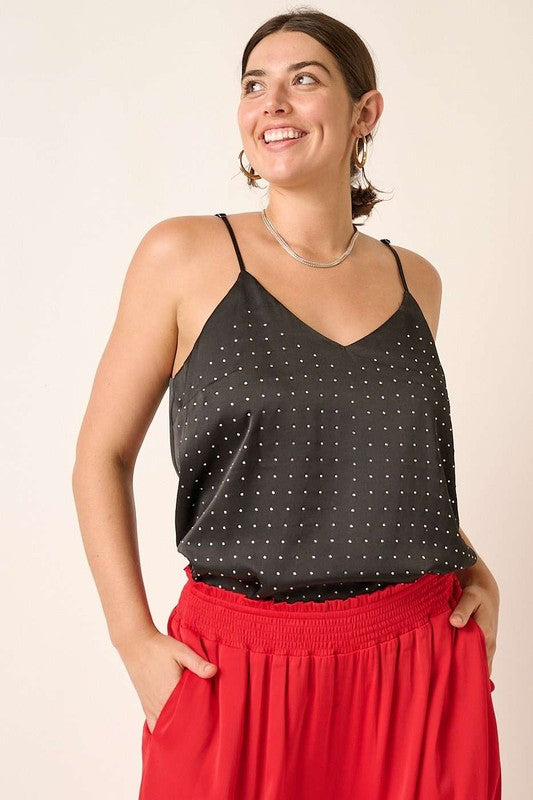 Woman wearing a black polka dot top and red pants against a beige background