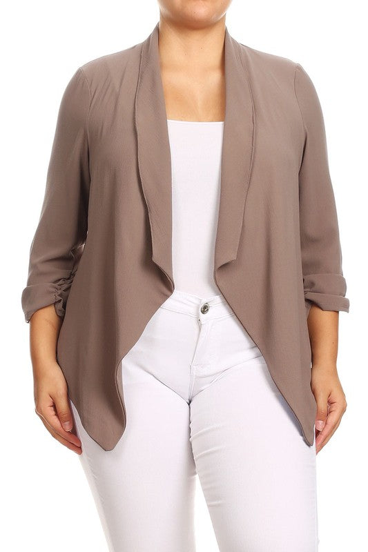 Person wearing a brown cardigan over a white top and white pants on a white background