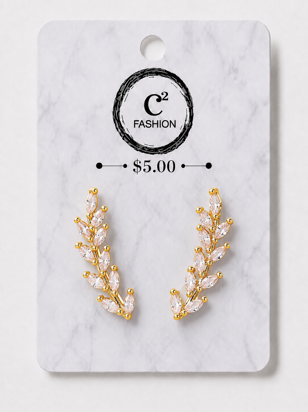 A pair of gold leaf-shaped stud earrings with marquise-cut clear crystals, displayed on a white marble backing card with the brand logo 'C2 FASHION' and a price of '$5.00'.