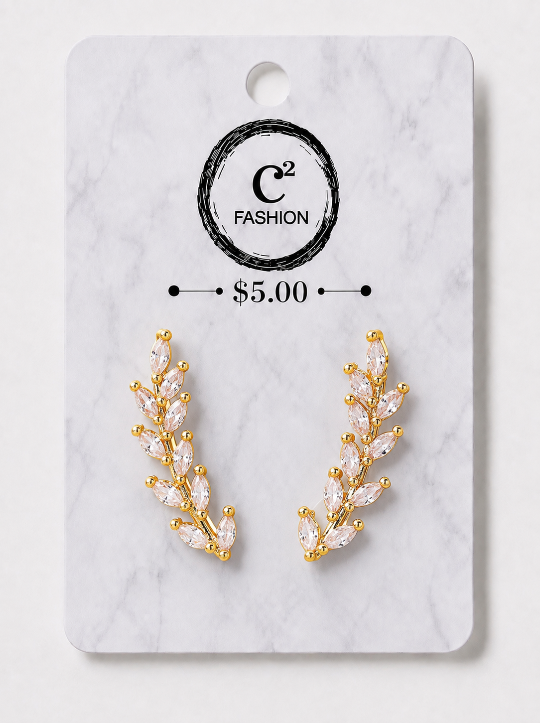 A pair of gold leaf-shaped stud earrings with marquise-cut clear crystals, displayed on a white marble backing card with the brand logo 'C2 FASHION' and a price of '$5.00'.