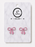 A pair of pink bow stud earrings displayed on a white marble backing card with a black circular logo that reads 'C2 FASHION' and a price of '$3.00'.
