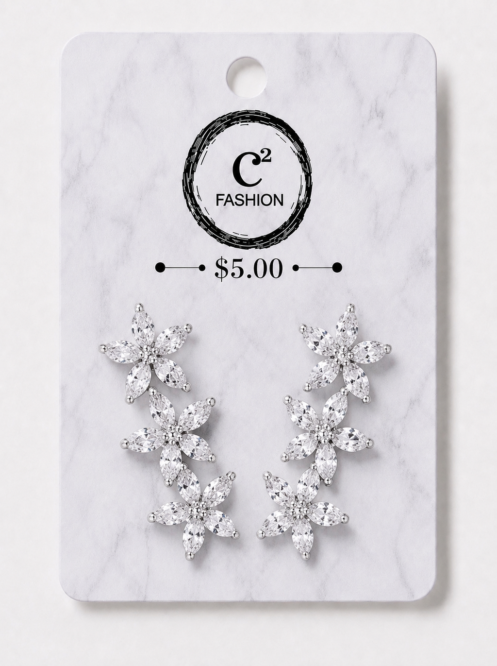 A pair of silver-toned dangle earrings with clear crystal-like floral clusters, displayed on a white marble-style retail card with the brand name C² FASHION and a $5.00 price printed on it.