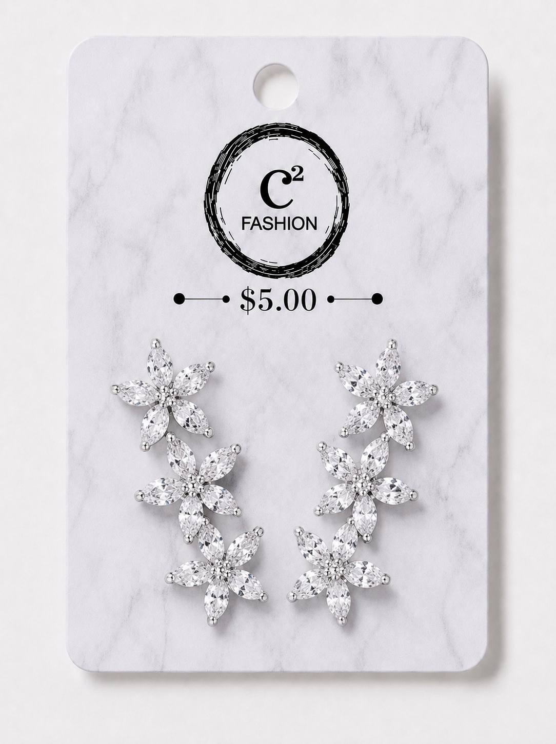A pair of silver-toned dangle earrings with clear crystal-like floral clusters, displayed on a white marble-style retail card with the brand name C² FASHION and a $5.00 price printed on it.