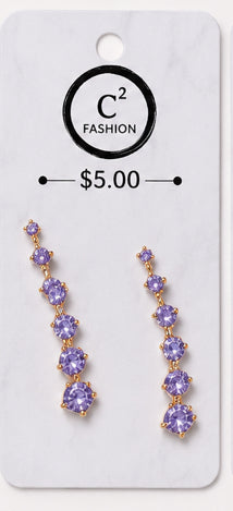 A pair of gold-tone drop earrings with purple gemstones, displayed on a white C2 Fashion retail card showing a $5.00 price.