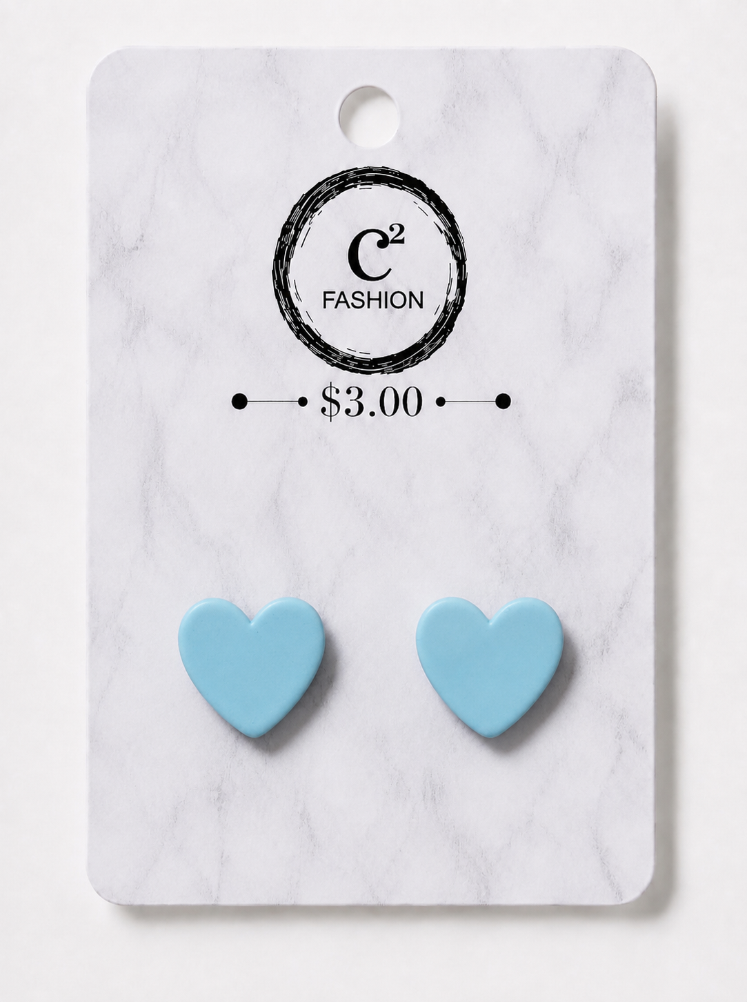A pair of light blue heart-shaped stud earrings displayed on a white marble-patterned retail card with the C2 FASHION logo and $3.00 price printed on it.