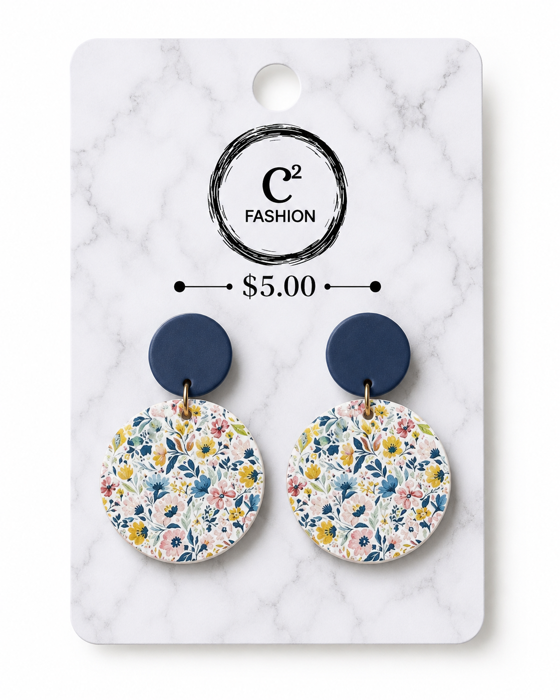 A pair of drop earrings displayed on a white marble backing card. The earrings have dark navy blue top discs and circular lower discs with a colorful floral pattern in blue, yellow, pink, and green.