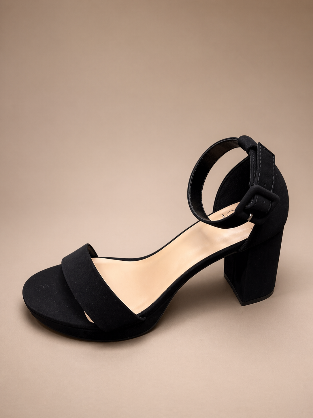 Black sandal with block heel on a beige background