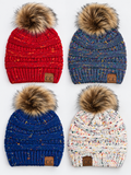 Four knit pom-pom beanies arranged in a 2x2 grid on a white background. The top-left is red with subtle orange/yellow flecks and a brown faux-fur pom-pom.