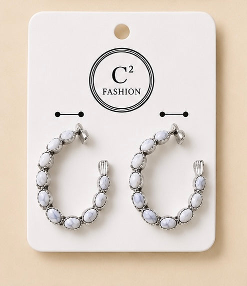 Silver-tone hoop earrings featuring oval white stones, displayed on a white C² Fashion jewelry card.