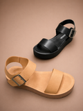 Black and tan sandals with buckles on a beige background
