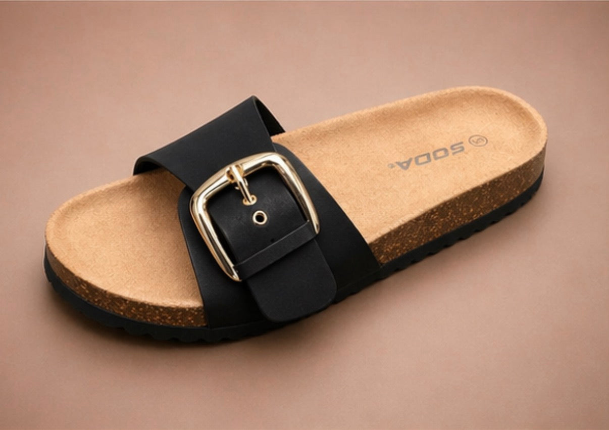 Birkenstock-style sandal with black strap and gold buckle on a beige background