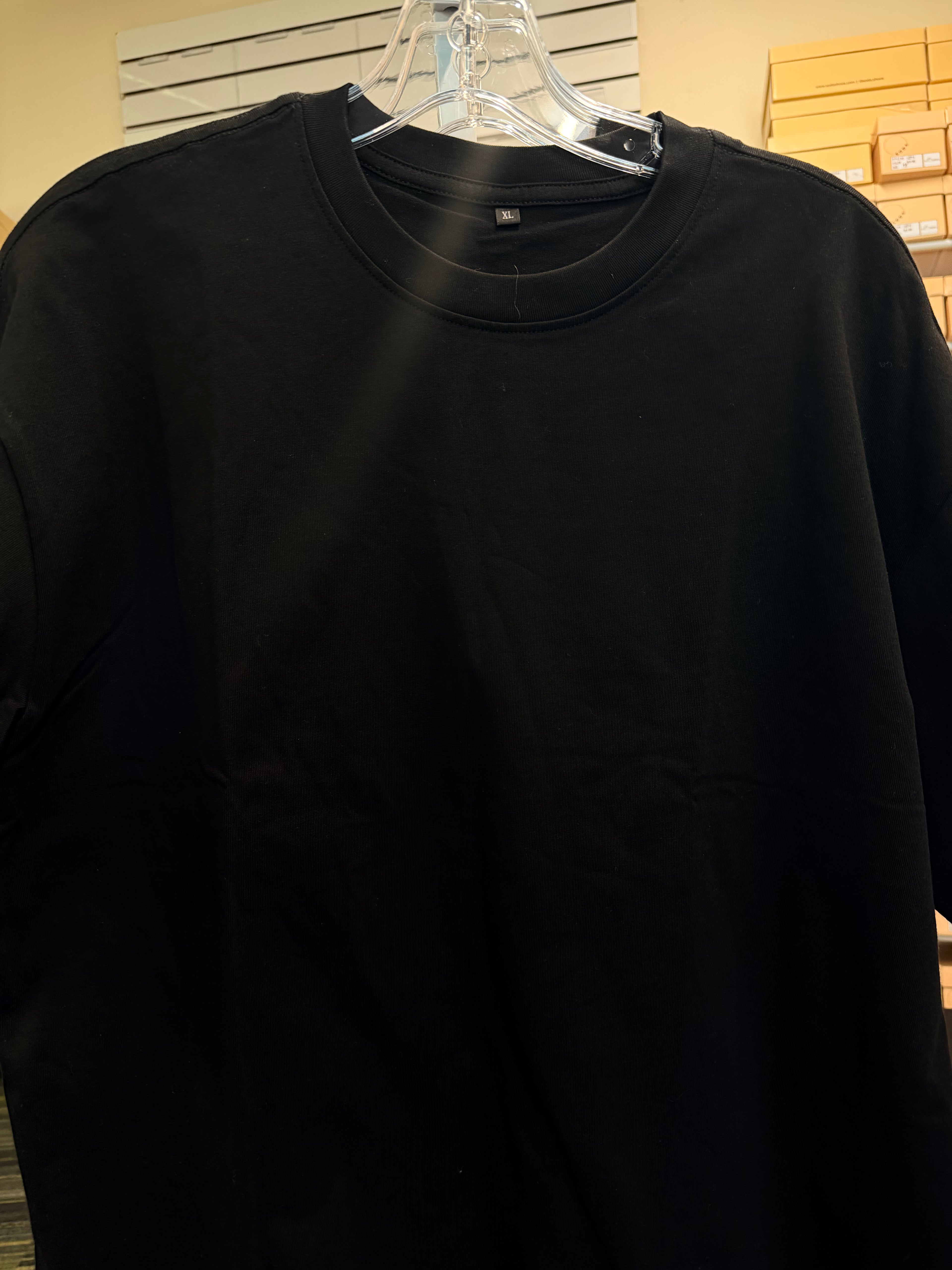 Black sweatshirt on a hanger against a neutral background