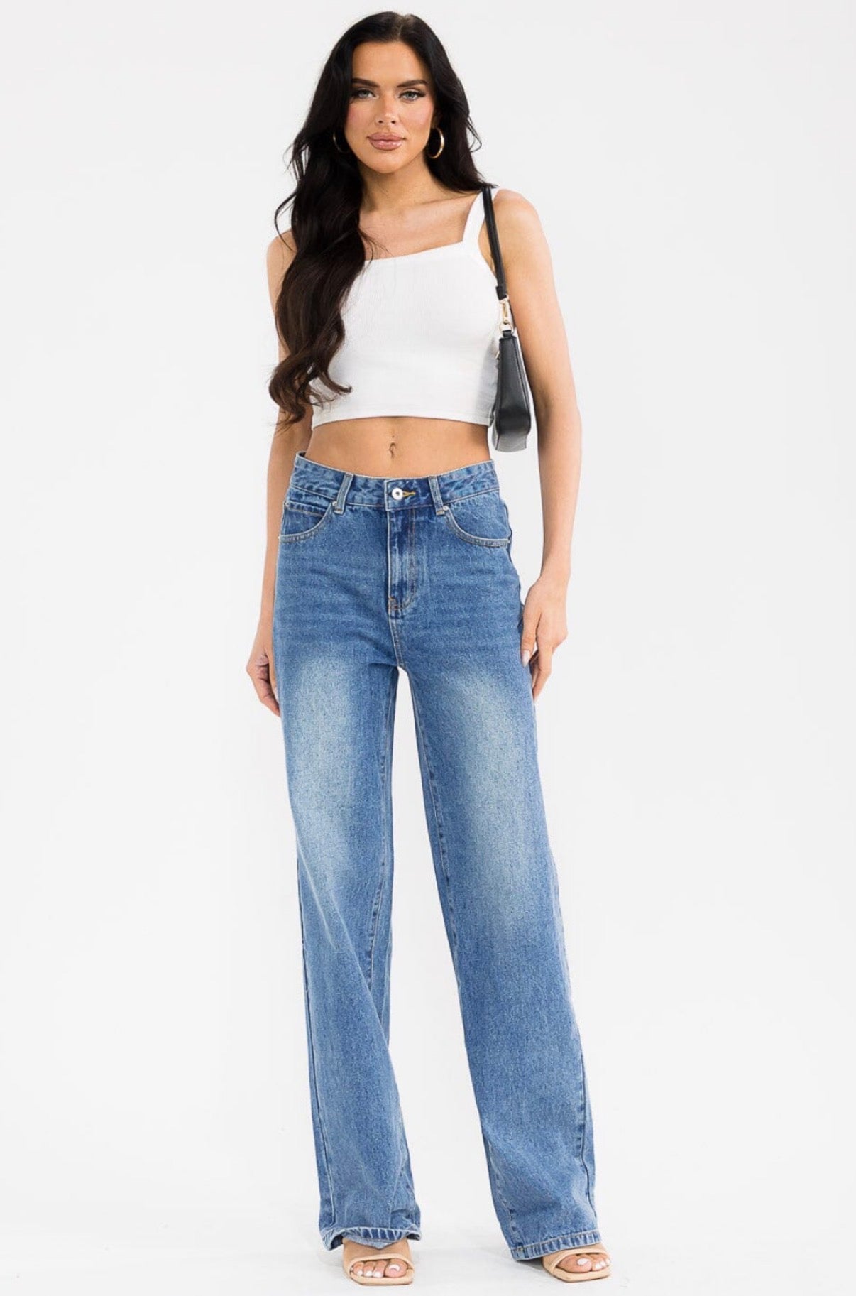 Woman wearing a white top and blue jeans on a white background