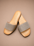 Pair of sandals with rhinestone straps on a beige background
