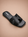 Black slide sandal with 'SODA' branding on a beige background
