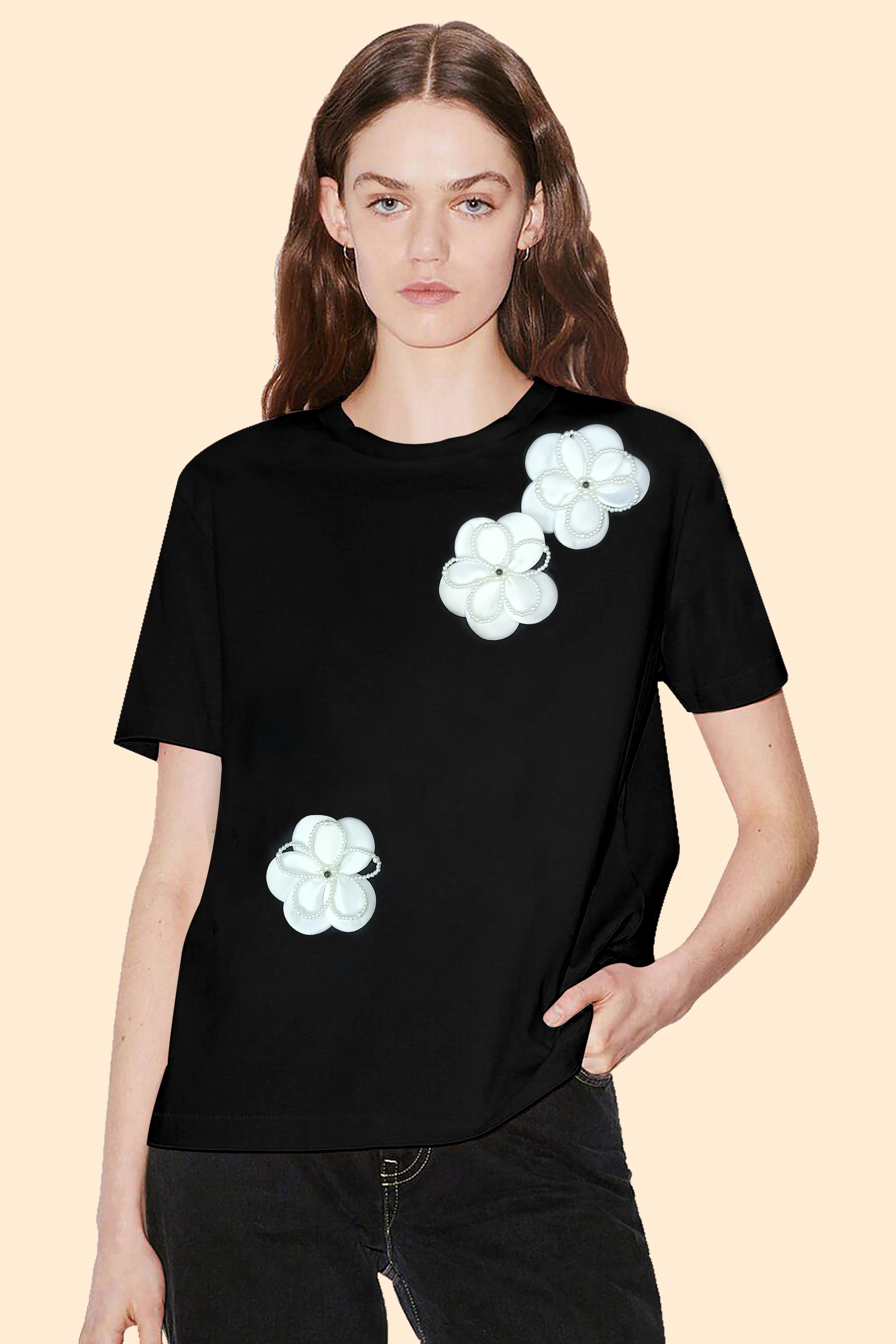 Person wearing a black t-shirt with white floral designs on a beige background