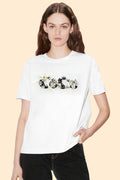 Woman wearing a white t-shirt with decorative elements on a beige background