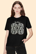 Person wearing a black t-shirt with lace details on the number 88 against a beige background
