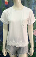 Mannequin wearing a white lace-trimmed top and denim shorts against a colorful floral background